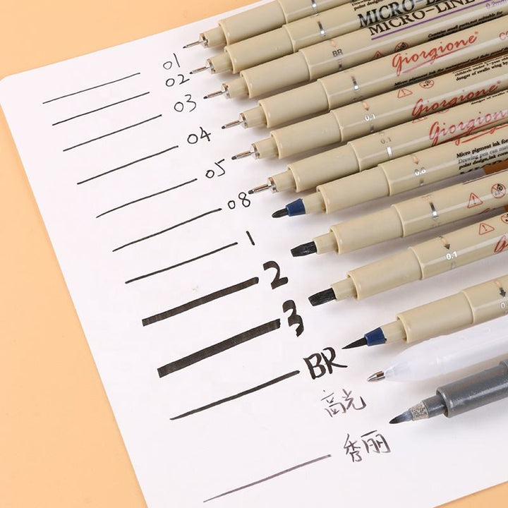 Set of Micron pens on a piece of paper with lines and text
