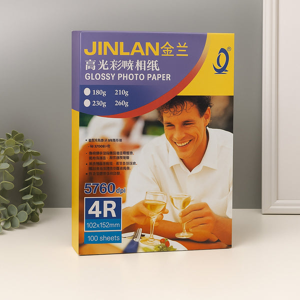 Box of JINLAN glossy photo paper with a man holding wine glasses on a white surface.