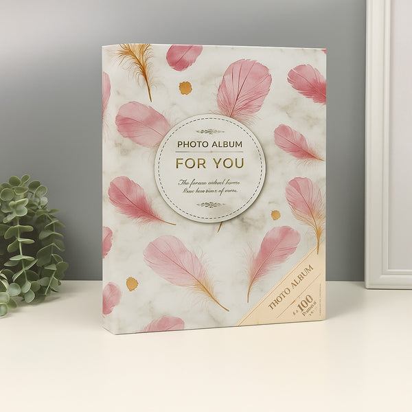 Photo album with pink feather design on a neutral background